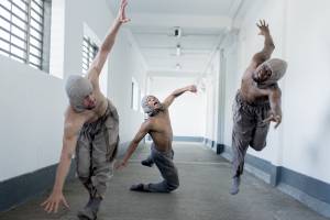 Three male dancers in a hallway moving towards the camera